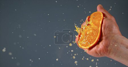 Photo for Hand of Man Squeezing Orange against Black Background - Royalty Free Image