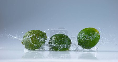 Foto de Limones verdes, cítricos aurantifolia, Frutas que caen sobre el agua - Imagen libre de derechos