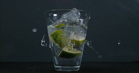 Foto de Cítricos verdes, cítricos aurantifolia, cayendo en un vaso de agua, - Imagen libre de derechos