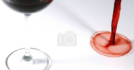 Foto de Vino tinto que se vierte en vidrio, contra fondo blanco - Imagen libre de derechos