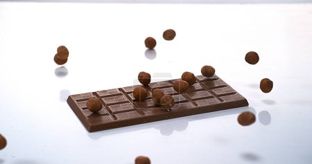 Foto de Avellanas cayendo en la tableta de chocolate con leche - Imagen libre de derechos