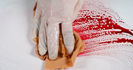 Téléchargez les photos : Main gantée qui essuie le sang sur fond blanc - en image libre de droit