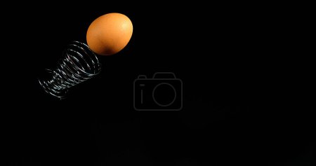 Photo for Egg and Egg Cup that bounce on black background - Royalty Free Image