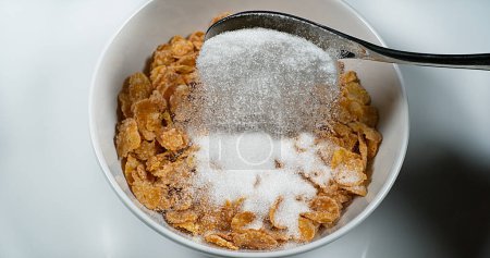 Téléchargez les photos : Sucre versé dans un bol de céréales - en image libre de droit