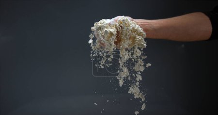 Téléchargez les photos : Mains d'homme à la farine sur fond noir - en image libre de droit