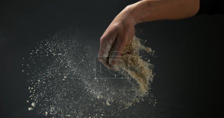 Téléchargez les photos : Mains d'homme à la farine sur fond noir - en image libre de droit