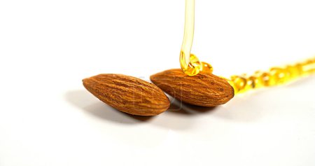 Photo for Honey Flowing on Almonds against White Background - Royalty Free Image