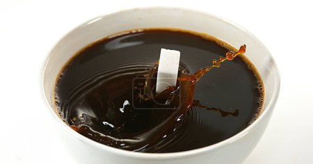 Foto de Azúcar cayendo en tazón de café contra fondo blanco - Imagen libre de derechos