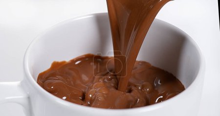 Téléchargez les photos : Chocolat Versant dans un bol sur fond blanc - en image libre de droit