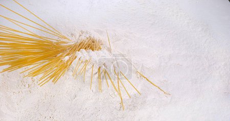 Foto de Pasta cayendo sobre harina contra fondo blanco - Imagen libre de derechos