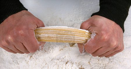 Foto de Manos de hombre rompiendo pasta de espagueti contra fondo de harina - Imagen libre de derechos