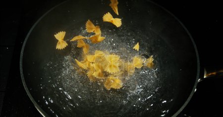 Photo for Pasta falling into boiling water - Royalty Free Image
