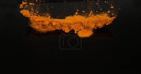 Foto de Cúrcuma, curcuma longa, Polvo cayendo sobre fondo negro, Especia india - Imagen libre de derechos