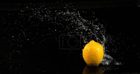 Téléchargez les photos : Jaune citron, Citrus limonum, Fruits tombant dans l'eau sur fond noir - en image libre de droit