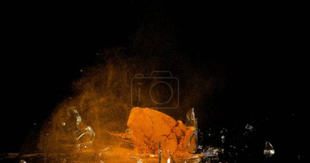 Téléchargez les photos : Curcuma, curcuma longa, Poudre dans un petit pot explosant sur fond noir, Épice indienne - en image libre de droit