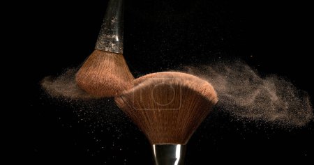Foto de Cepillo de maquillaje que extiende el polvo de rubor sobre fondo negro - Imagen libre de derechos