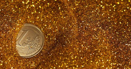 Foto de Moneda de 1 euro rodando en polvo de oro contra fondo negro - Imagen libre de derechos
