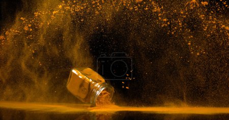 Photo for Turmeric, curcuma longa, Powder into a small jar falling against Black Background, Indian Spice - Royalty Free Image