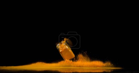 Téléchargez les photos : Curcuma, curcuma longa, Poudre dans un petit pot tombant sur fond noir, Épice indienne - en image libre de droit