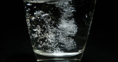 Photo for Water being poured into Glass against Black Background - Royalty Free Image