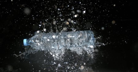Foto de Botella de agua cayendo sobre el agua contra fondo negro - Imagen libre de derechos