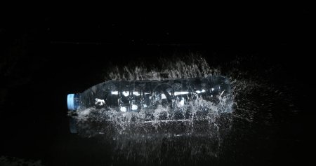 Téléchargez les photos : Bouteille d'eau tombant sur l'eau sur fond noir - en image libre de droit