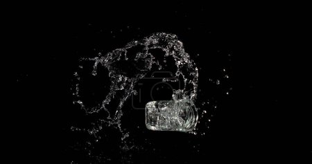 Téléchargez les photos : Verre d'eau rebondissant et éclaboussant sur fond noir - en image libre de droit