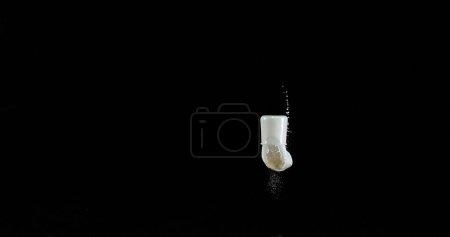 Téléchargez les photos : Verre de lait rebondissant et éclaboussant sur fond noir - en image libre de droit