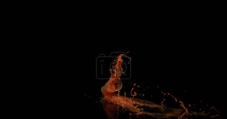 Foto de Vaso de jugo de tomate rebotando y salpicando sobre fondo negro - Imagen libre de derechos