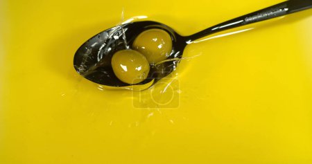 Photo for Green Olive, Olea europaea, Falling in a Spoon - Royalty Free Image
