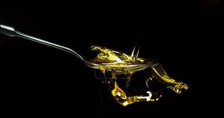 Foto de Aceite de oliva, cayendo en una cuchara sobre fondo negro - Imagen libre de derechos