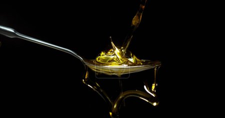 Photo for Olive Oil, Falling in a Spoon against Black Background - Royalty Free Image