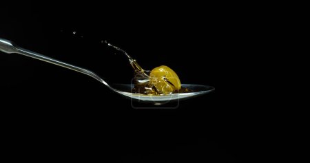 Photo for Green Olive, Olea europaea, Falling in a Spoon against Black Background - Royalty Free Image