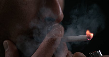 Foto de Hombre fumando un cigarrillo contra fondo negro - Imagen libre de derechos