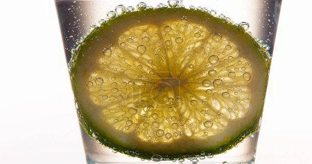 Téléchargez les photos : Tranche de citron vert, agrumes aurantifolia, dans un verre - en image libre de droit