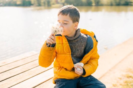 A ten-year-old teenage boy is standing outdoors with a runny nose and cough, showing symptoms of springtime allergies caused by blooming spring flowers such as pollen and blossoms. High quality photo