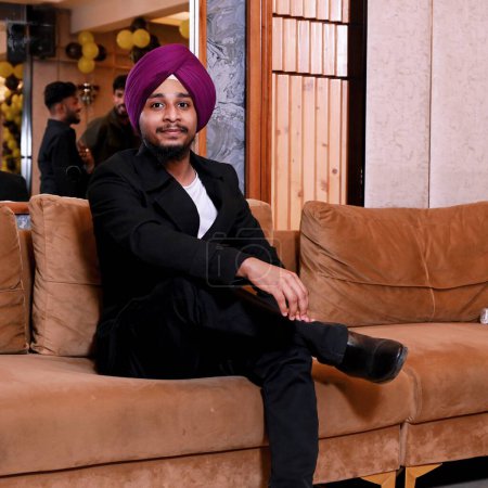 Sikh Boy Sitting On Sofa With Black LongCoat