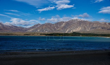 The shoreline of Lake Tekapo New Zealand on a beautiful but cold afternoon. The colour of the water is altered by the silt washing down after snow melting.