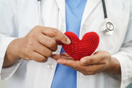 Asian doctor holding red heart in hospital, cardiovascular disease, CVD.