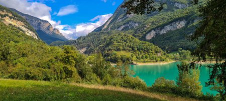 Beautiful green lake Lago di Tenno between green forest mountains.