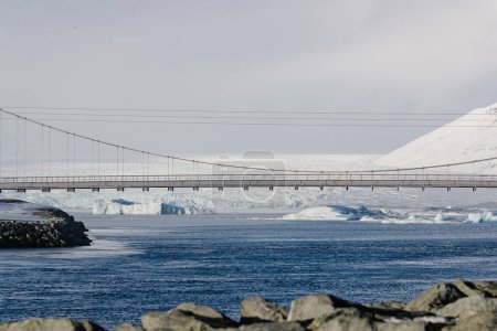 Vehicle Crossing Suspension Bridge over Glacial River