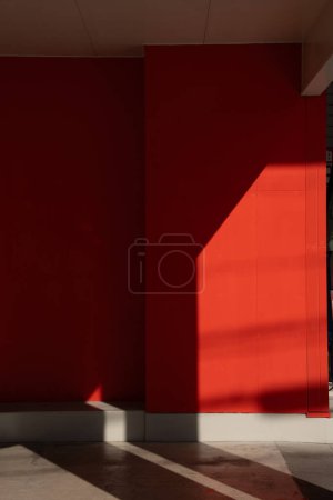 Photo for Dramatic shadow play on a bold red wall in urban setting - Royalty Free Image