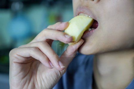 Photo for Asian woman is biting on Apple, closed up shot on her mouth eating. - Royalty Free Image