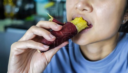 Photo for Asian woman is eating Sweet Potatoes, closed up shot. - Royalty Free Image