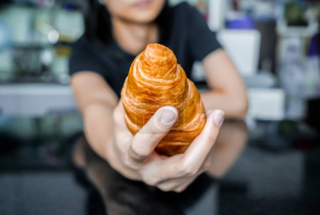 Photo for Woman holding a croissant in her hand, closed up shot. - Royalty Free Image