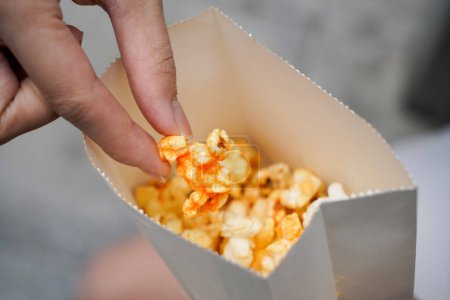 Photo for Woman holding popcorn cheese in a paper bag  in the hand - Royalty Free Image
