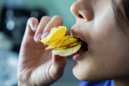 Photo for Woman using her hand to eat potato chips from a bowl, closed up shot. - Royalty Free Image