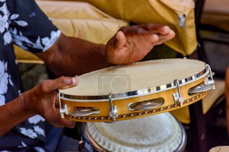 Téléchargez les photos : Mains et instrument de musicien jouant du tambourin dans les rues de Salvador à Bahia lors d'une performance de samba pendant le carnaval - en image libre de droit