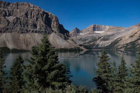 Découvrez la beauté à couper le souffle de l'Alberta avec cette superbe photographie d'un lac glaciaire. Les eaux cristallines, encadrées par des sommets majestueux et des forêts luxuriantes à feuilles persistantes, créent une scène d'une splendeur naturelle inégalée. 