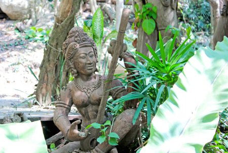 Eine antike Statue ist von üppigem Grün umgeben und offenbart kulturelles Erbe und handwerkliche Tradition